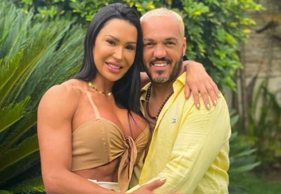 Gracyanne Barbosa e Belo sorriem abraçados no jardim 