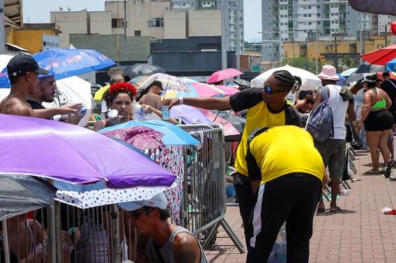 Funcionários distribuindo água para pessoas na fila