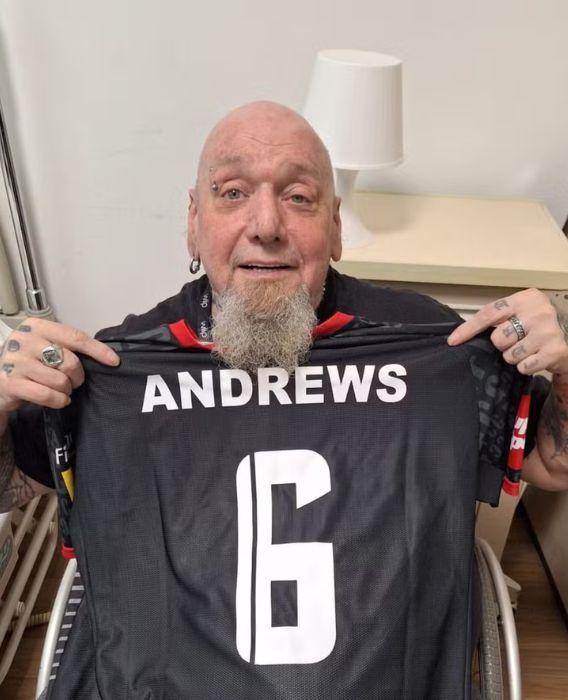 Paul Di'Anno, na cadeira de rodas, segura uma camisa de futebol