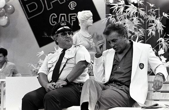 o ator roberto marquis como guarda juju sentado no banco da praça ao lado de carlos alberto de nóbrega