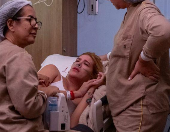 Lore Improta na cama do hospital ao lado de médicas